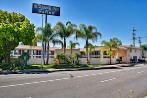 Un hotel con un letrero que dice 'Bank Inn Suites' y un edificio de dos pisos con techo plano y fachada color beige.