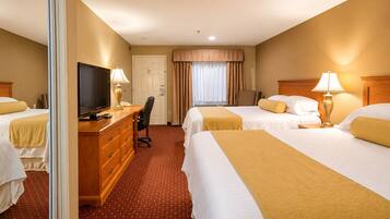A hotel room with two beds, a desk with a television, and a chair.