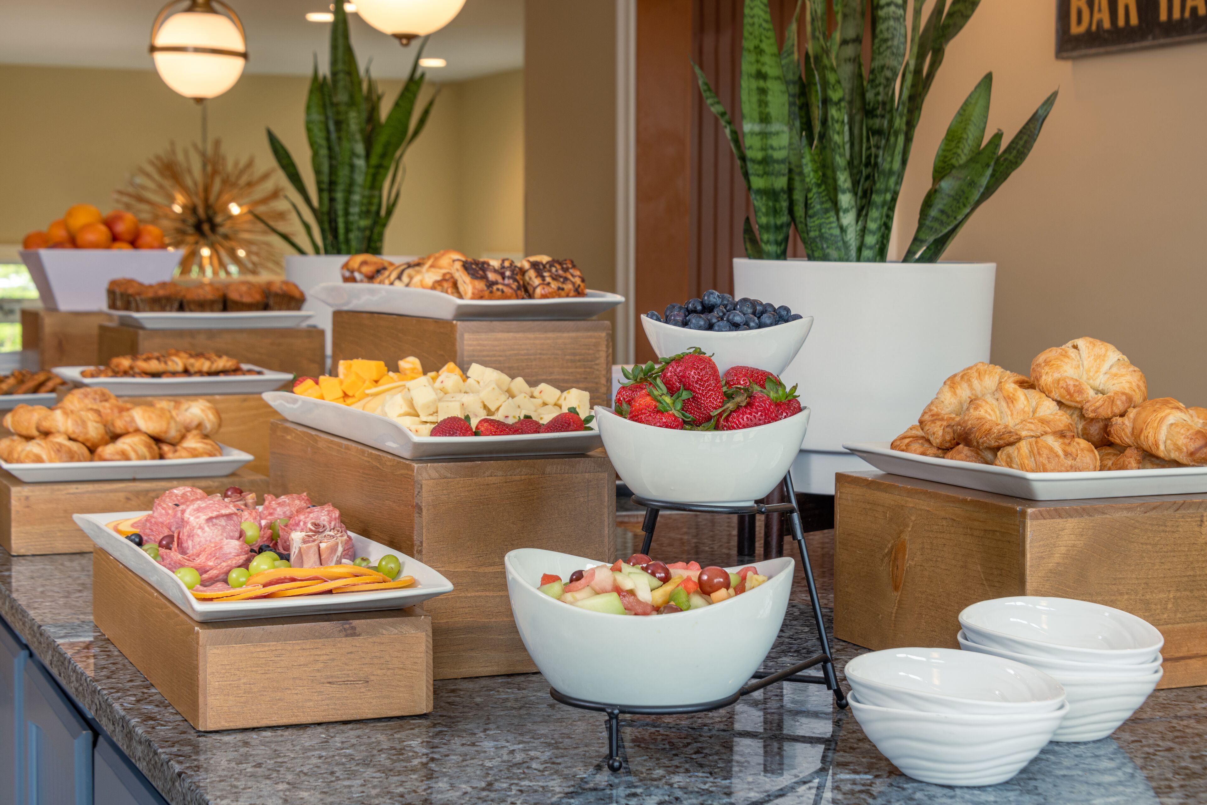 A buffet with various food items including fruits, pastries, and meats.