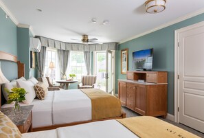 Une chambre d’hôtel équipée d’un lit, d’un bureau, d’une télévision, d’une armoire et d’une fenêtre avec des rideaux.