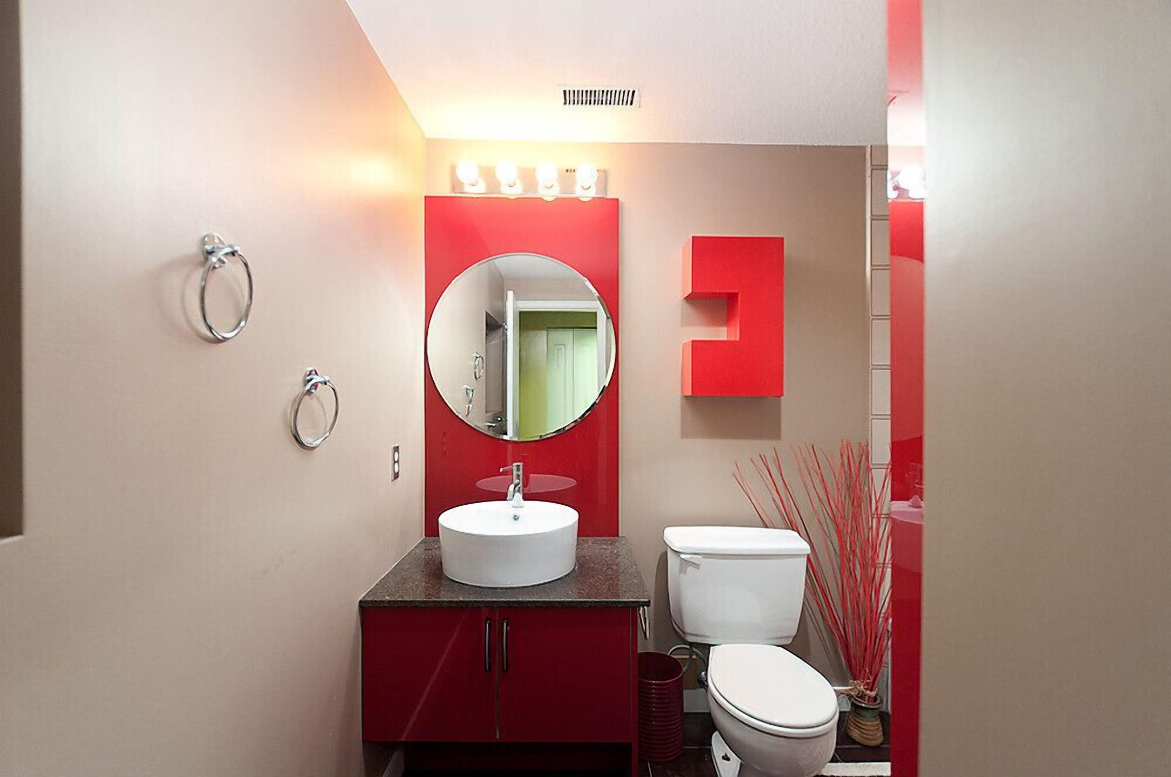 A bathroom with a round mirror, a white sink, and a toilet.