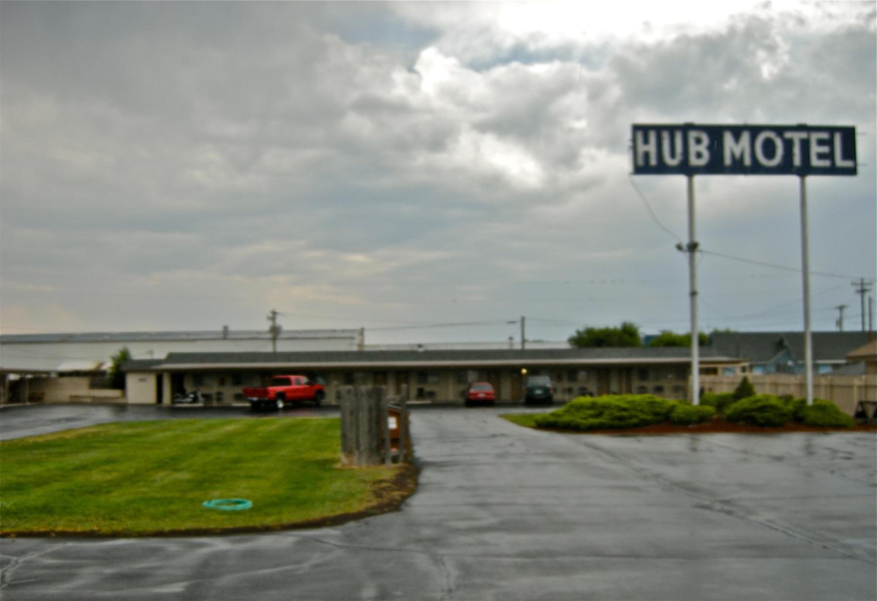 A HUB MOTEL with a parking lot and a building in the background.
