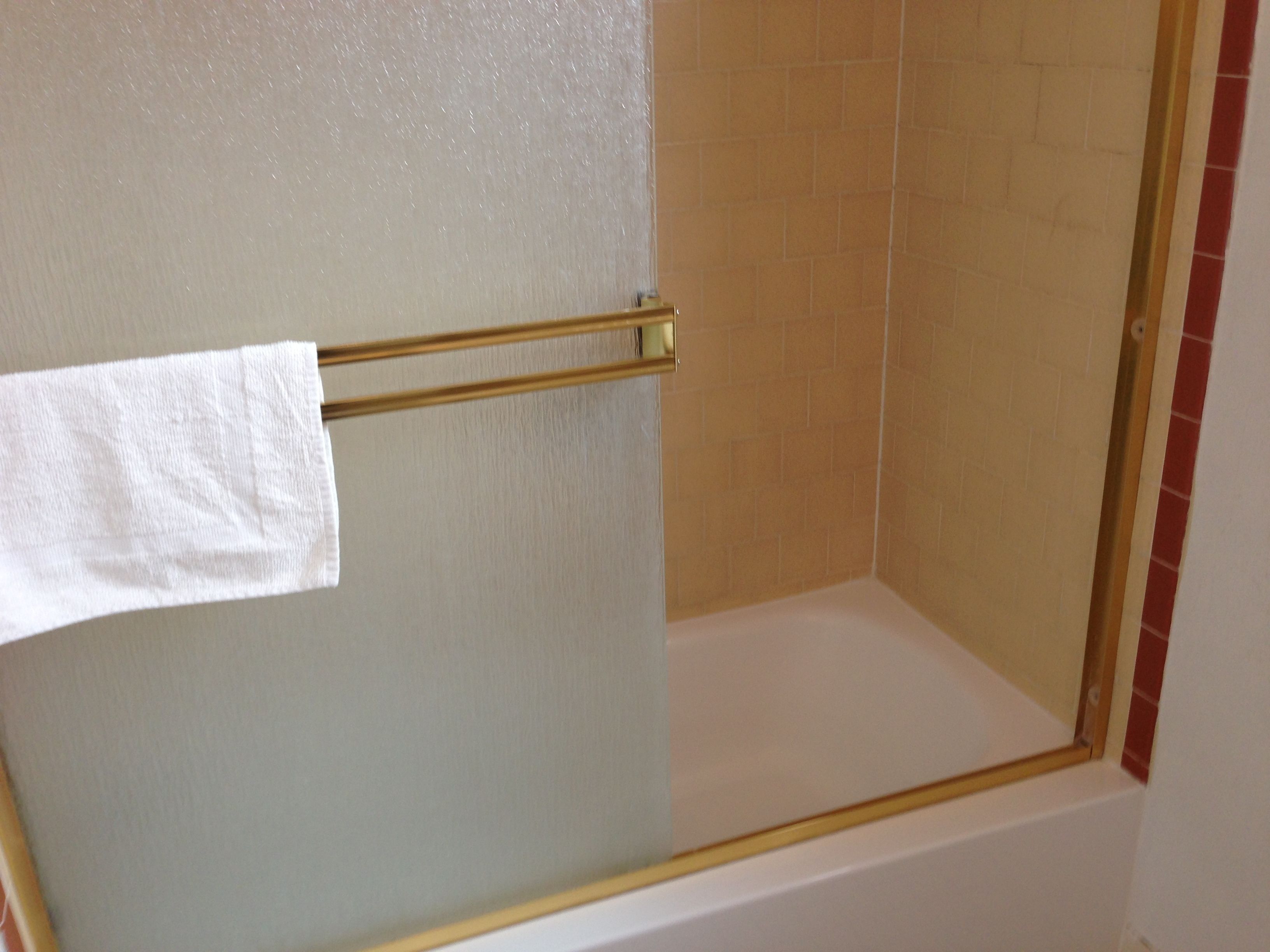 A shower with a glass door and a towel rack.