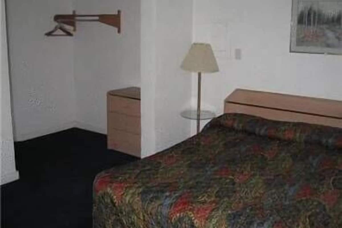 Une chambre d’hôtel avec un lit, une table de chevet, une lampe et un tableau au mur.