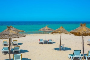 A beach with thatched umbrellas and lounge chairs. - Neptunia Beach (Monastir)