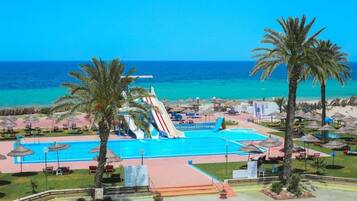 A resort with a swimming pool, palm trees, and a water slide.