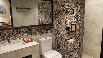 A bathroom with patterned tiles, a sink, a toilet, and a mirror.