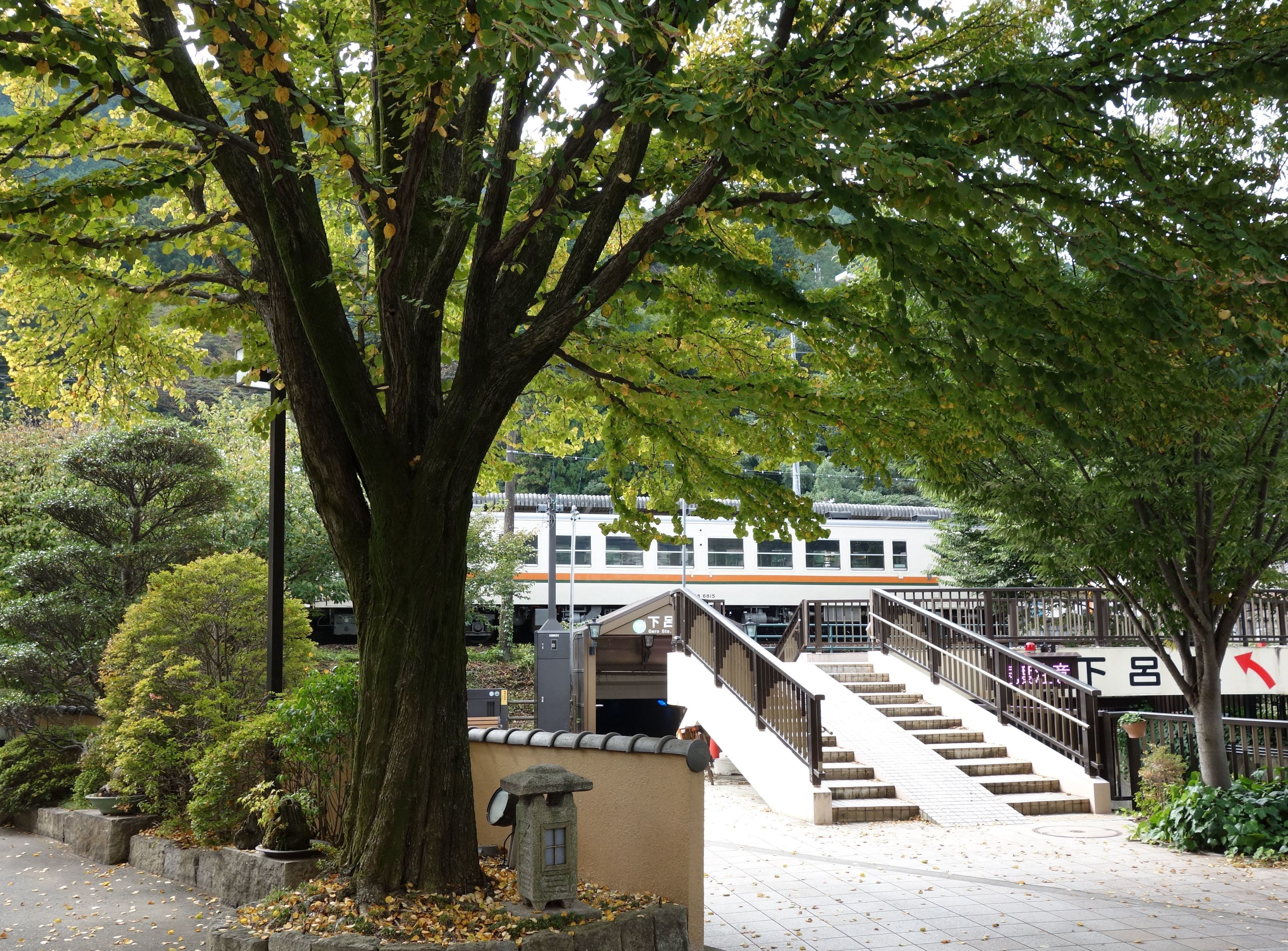 Un edificio de estilo japonés tradicional con un farol de piedra, un muro de piedra y una escalera que lleva a una entrada.