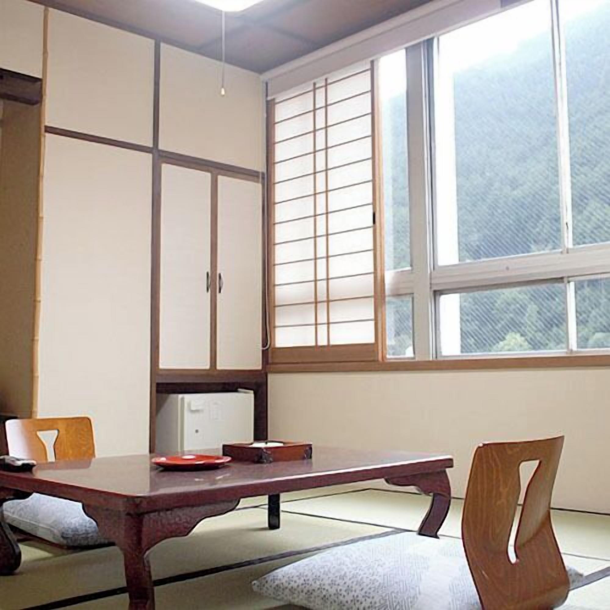 Une pièce de style japonais traditionnel, avec un sol recouvert de tatamis, une table basse et des portes coulissantes.