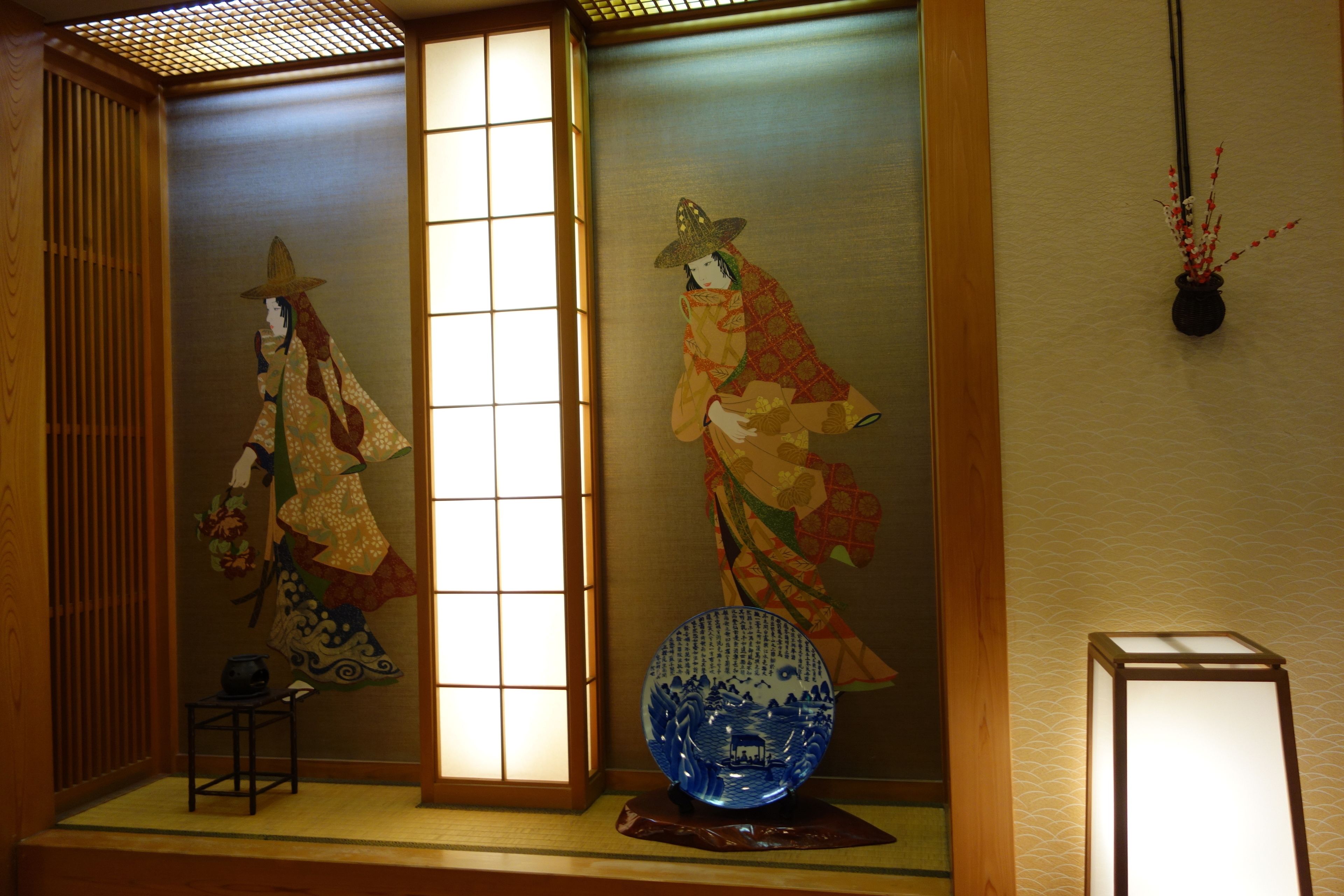 Una habitación japonesa tradicional con suelo de tatami, puertas correderas y un jarrón decorativo.