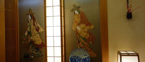 Una habitación japonesa tradicional con suelo de tatami, puertas correderas y un jarrón decorativo.