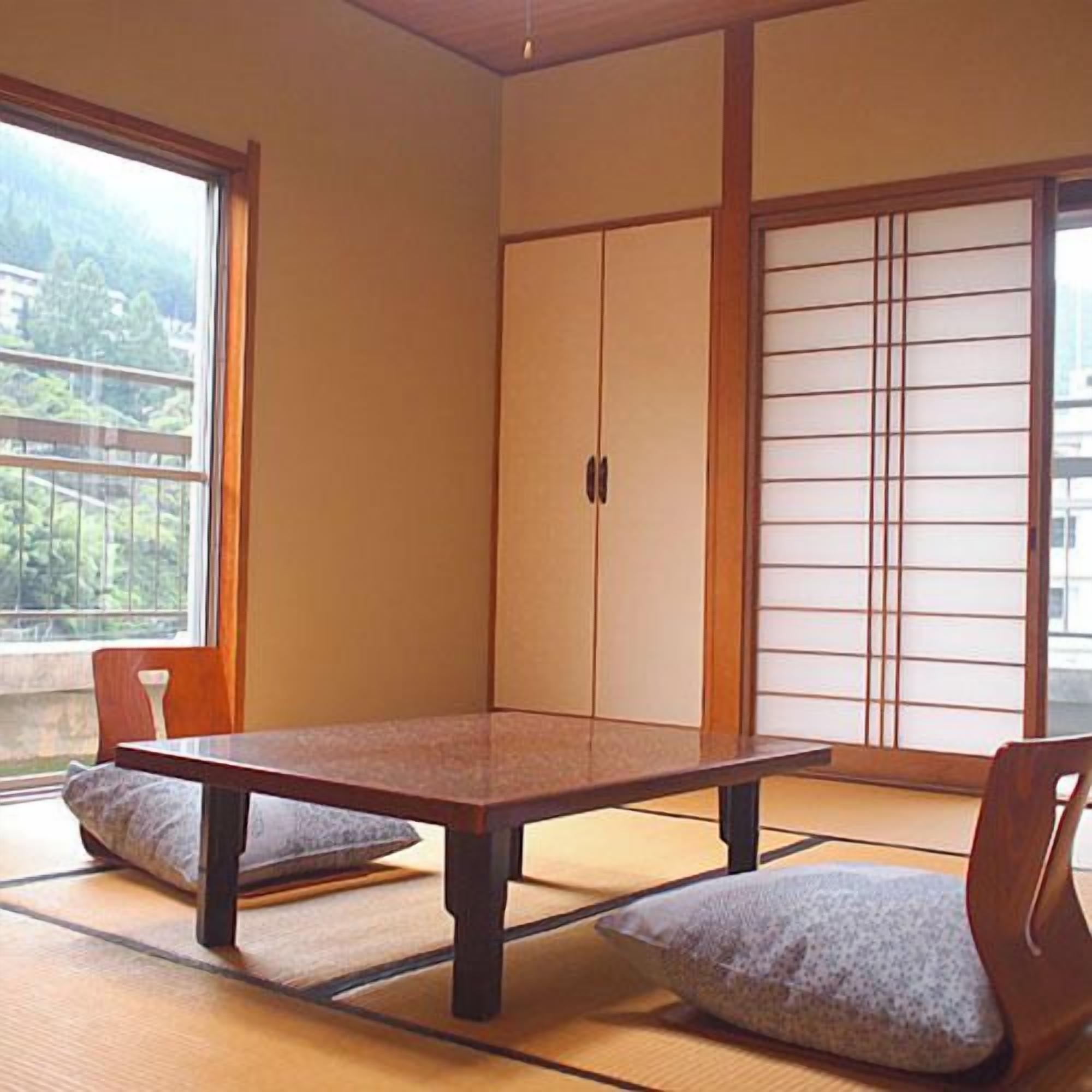 Une pièce de style japonais traditionnel, avec un sol recouvert de tatamis, une table basse et des portes coulissantes.