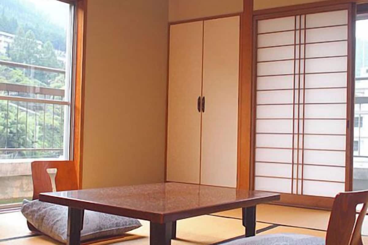 Une pièce de style japonais traditionnel, avec un sol recouvert de tatamis, une table basse et des portes coulissantes.