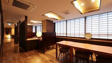 A traditional Japanese-style room with wooden flooring, tatami mats, low tables, and sliding doors.