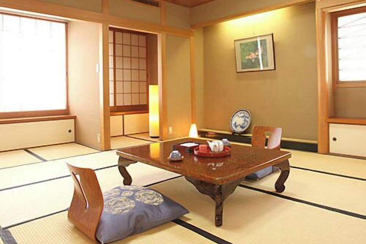 A traditional Japanese room with tatami flooring, a low wooden table, and a sliding door.