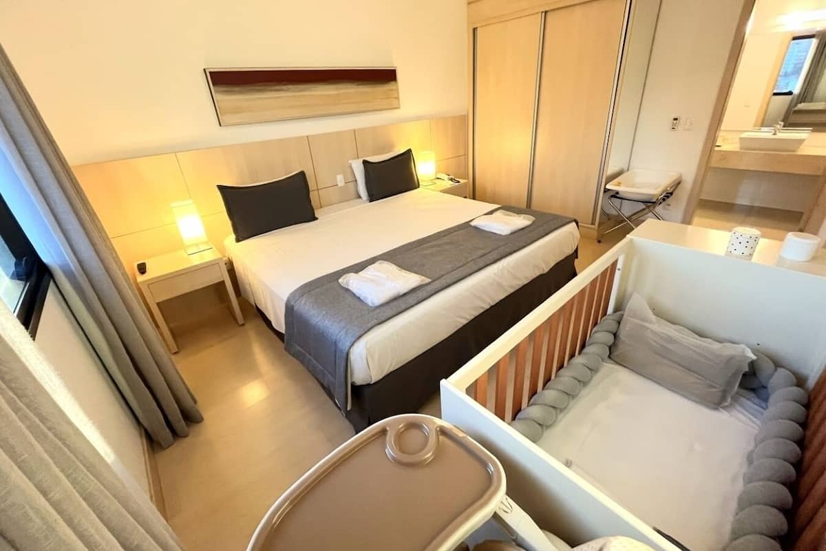 A hotel room with a bed, bedside tables, a desk, a chair, and a small table with a tray.