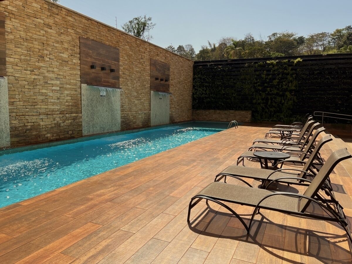A swimming pool with lounge chairs and a brick wall.