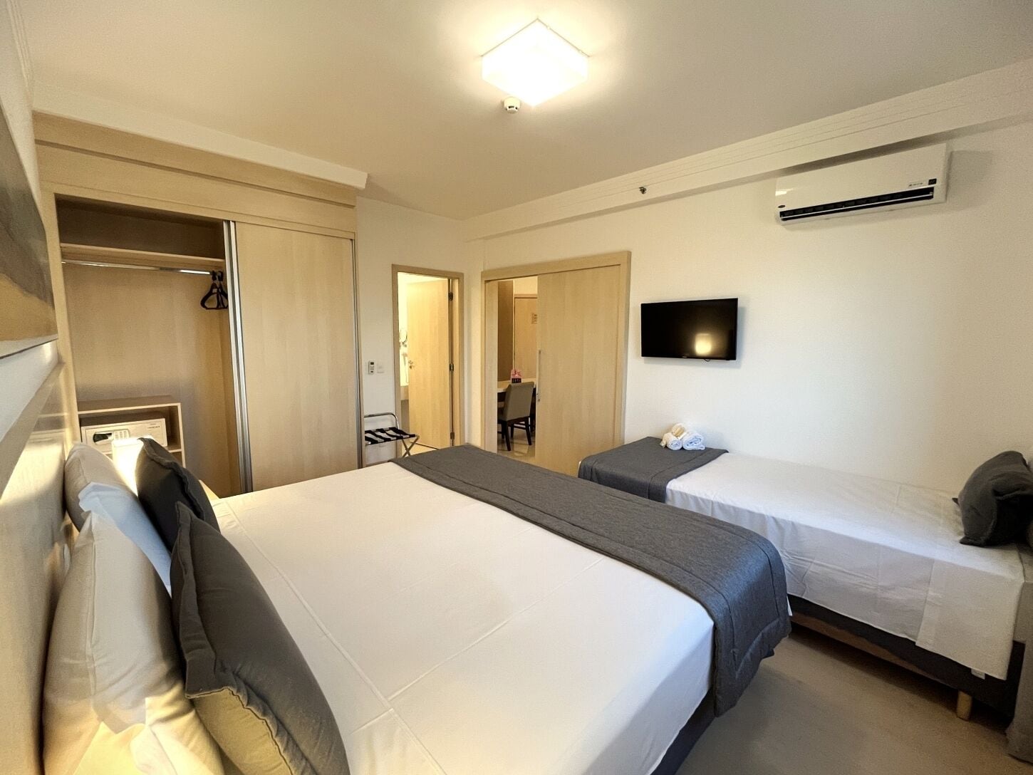 Hotelkamer met een groot bed, een kleiner bed, een televisie, een airconditioning en een kast.