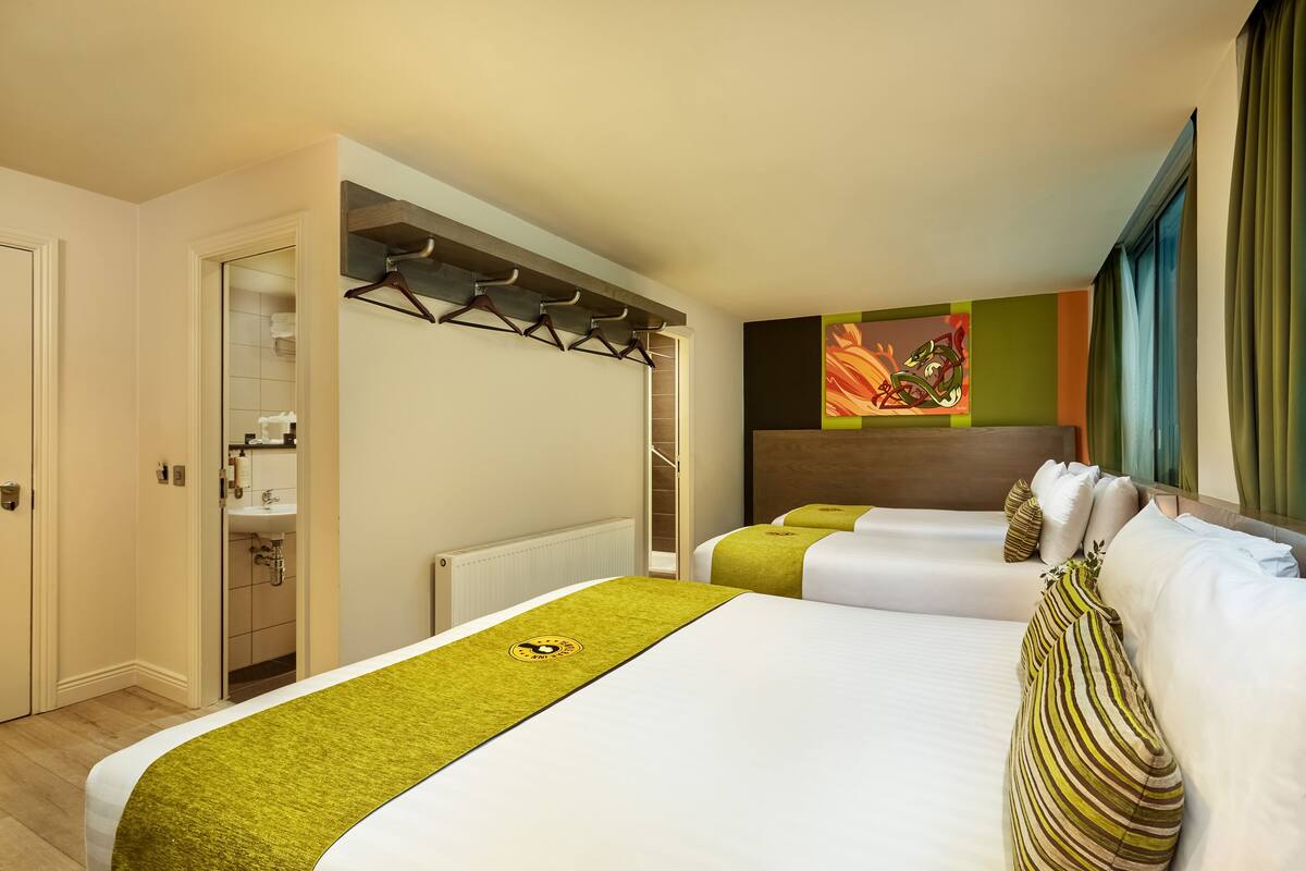 A hotel room with two beds, a bathroom, and a view of the city.