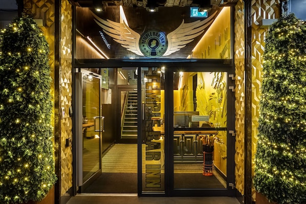 The entrance to Temple Bar Inn with a glass door, a Christmas tree on each side, and a winged logo above the entrance.