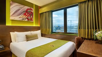 Habitación de hotel con una cama grande, un escritorio y una ventana con cortinas.