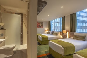 A hotel room with two beds, a bathroom, and a view of the city.