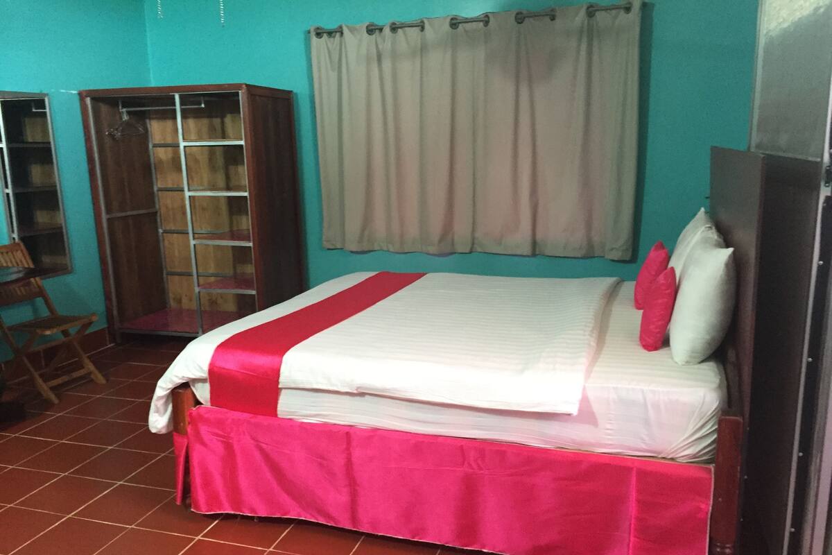 A bedroom with a bed, a wardrobe, a desk, and a chair.