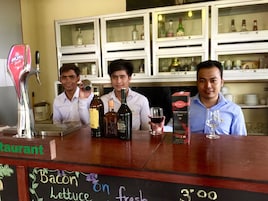 A bar area with bottles of alcohol, a chalkboard menu, and a cash register.