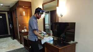 A hotel room with a wooden desk, a television, and a mirror. - Furaya Hotel (Pekanbaru)