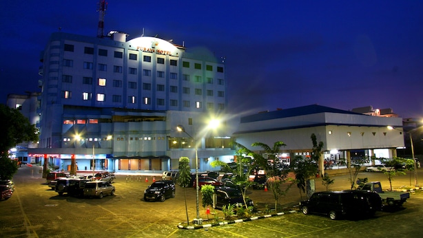 A hotel with multiple floors, a parking lot, and several vehicles parked. - Furaya Hotel (Pekanbaru)