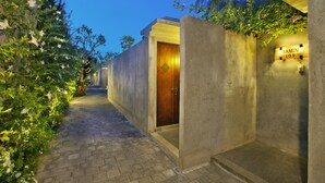 A narrow pathway leading to a building entrance with a wooden door, a concrete wall, and a sign reading "RAMIN 109". - Bracha Villas (Seminyak)