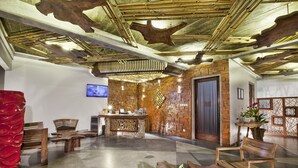A lobby with a wooden reception desk, seating area, and a unique ceiling design. - Bracha Villas (Seminyak)