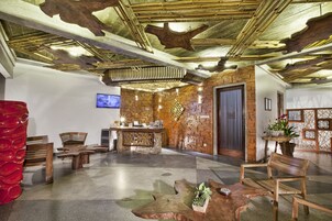 Un vestíbulo con mostrador de recepción de madera, zona de estar y un diseño de techo único.