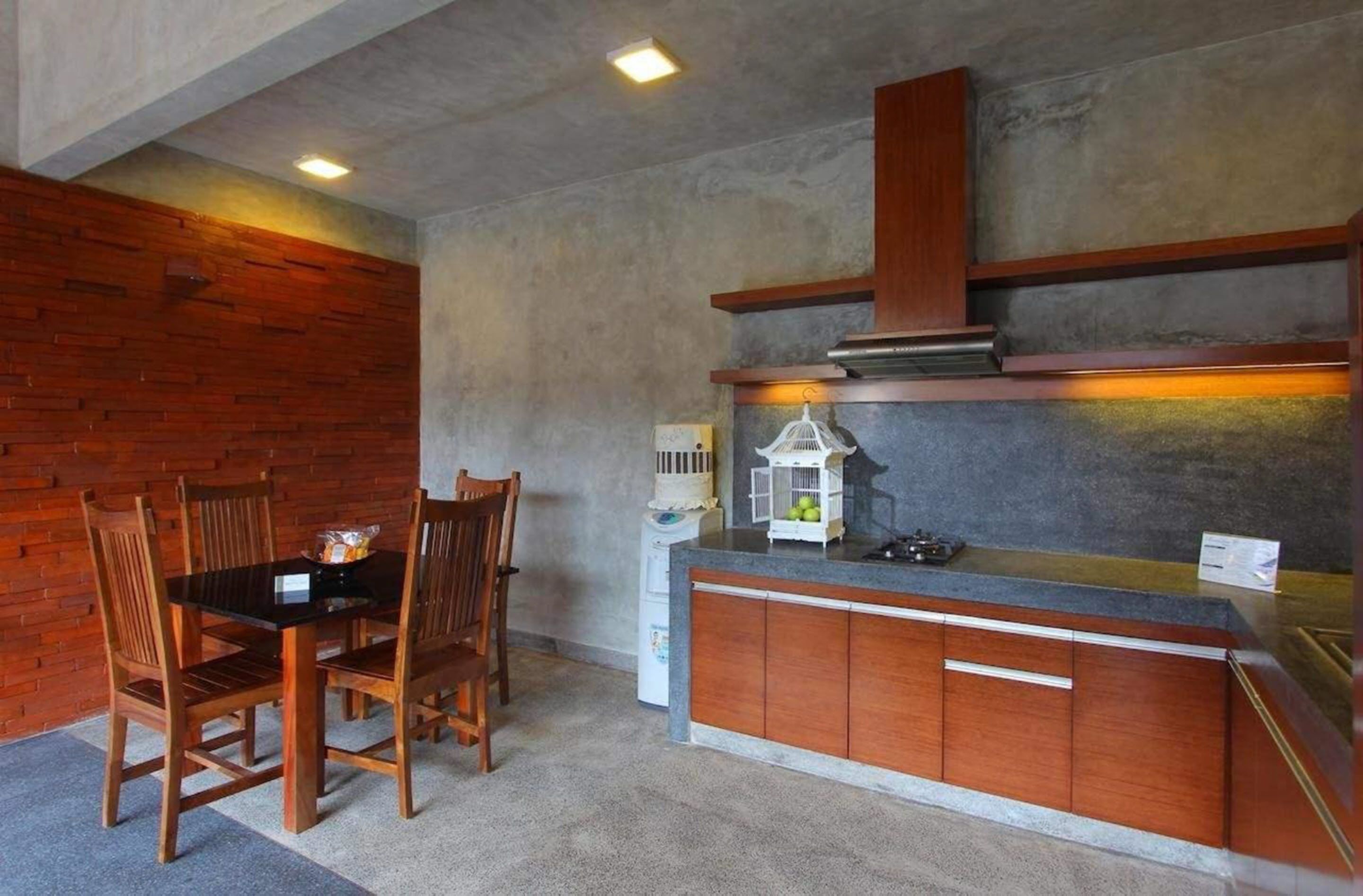 A compact kitchen with a dining table and chairs, a small island with a sink, and a brick accent wall.