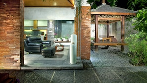 A modern interior with a brick wall, leather sofa, and a glass partition. - Bracha Villas (Seminyak)