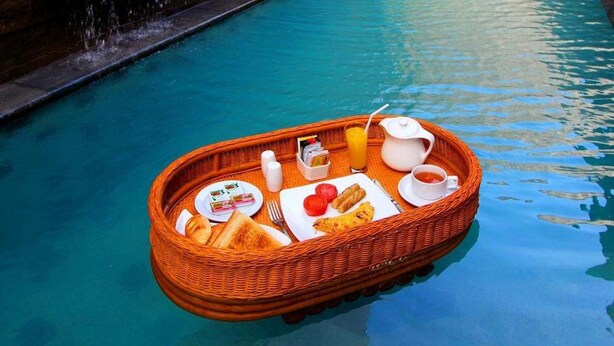 A floating breakfast tray with toast, eggs, tomatoes, and beverages on a pool. - Bracha Villas (Seminyak)