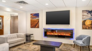 A modern living room with a fireplace, a sofa, a chair, and artwork on the walls. - Best Western Plus Service Inn & Suites (Lethbridge)