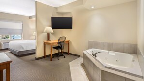 A hotel room with a bed, desk, chair, TV, and a large bathtub. - Best Western Plus Service Inn & Suites (Lethbridge)