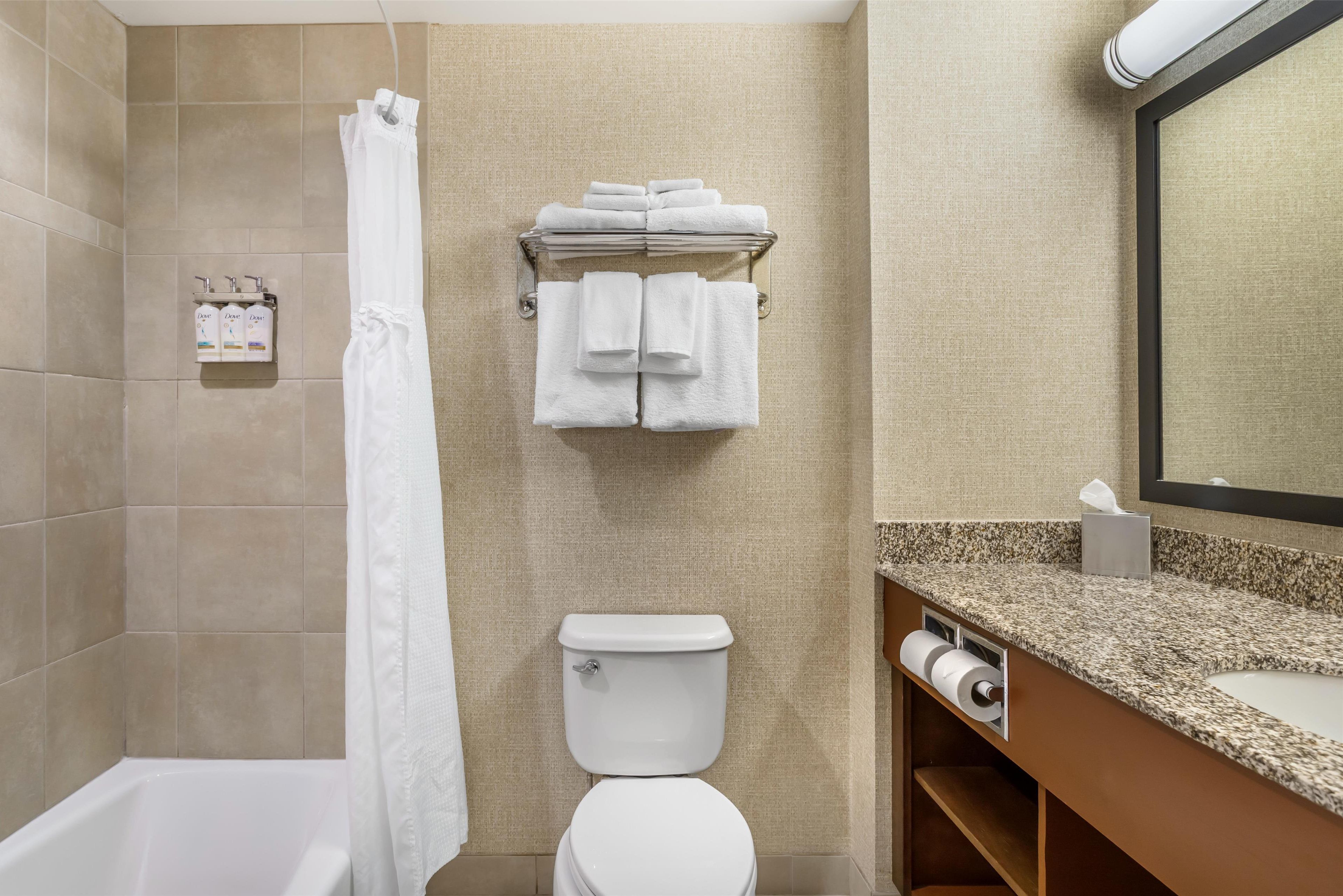 A bathroom with a bathtub, toilet, and a towel rack with folded towels.