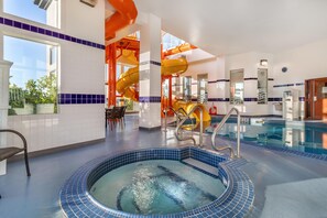 An indoor swimming pool with a hot tub, a slide, and a seating area with a view of the outdoors. - Best Western Plus Service Inn & Suites (Lethbridge)