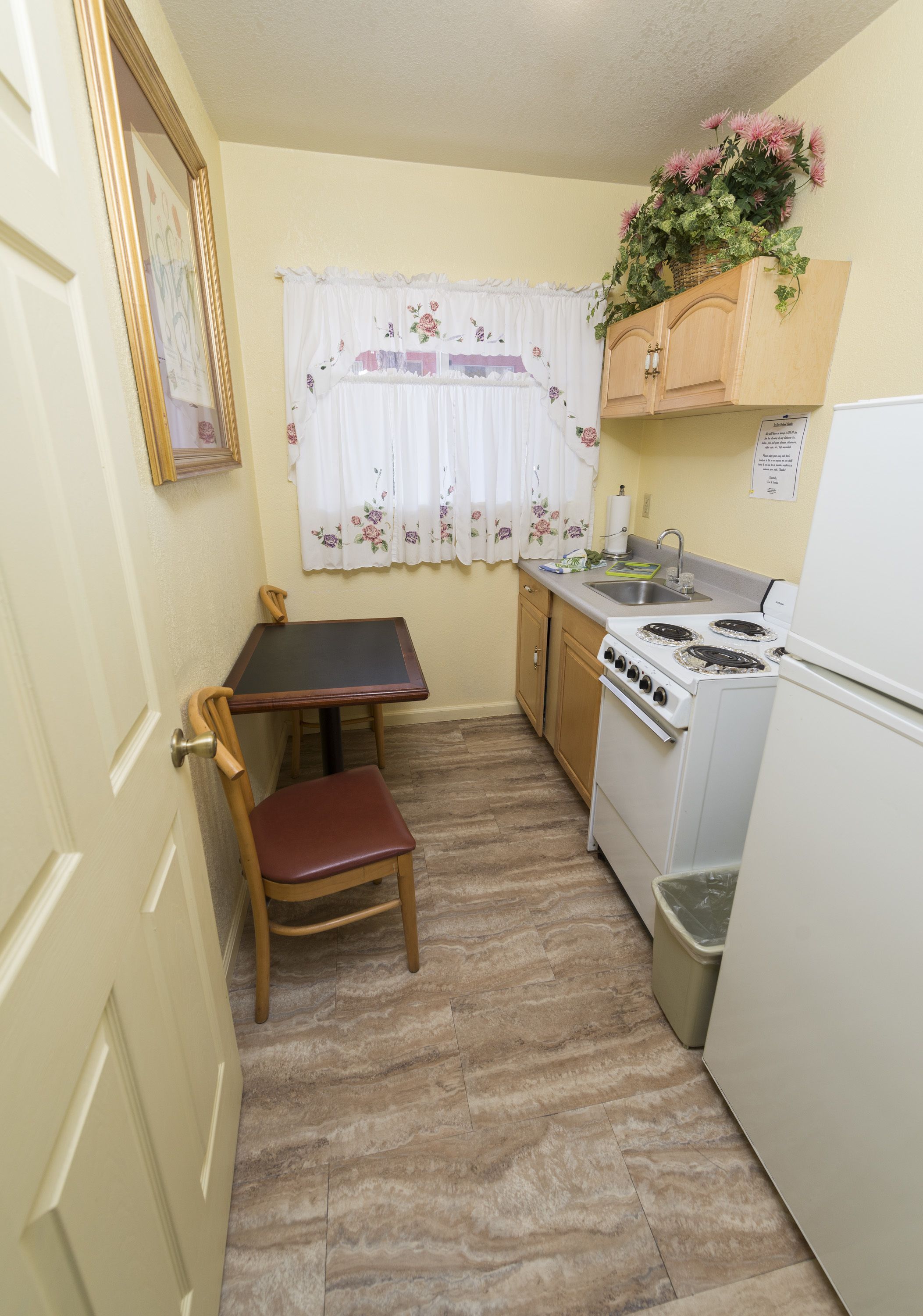 Une cuisine de taille réduite comprenant une table à manger, des chaises, une cuisinière et un réfrigérateur.