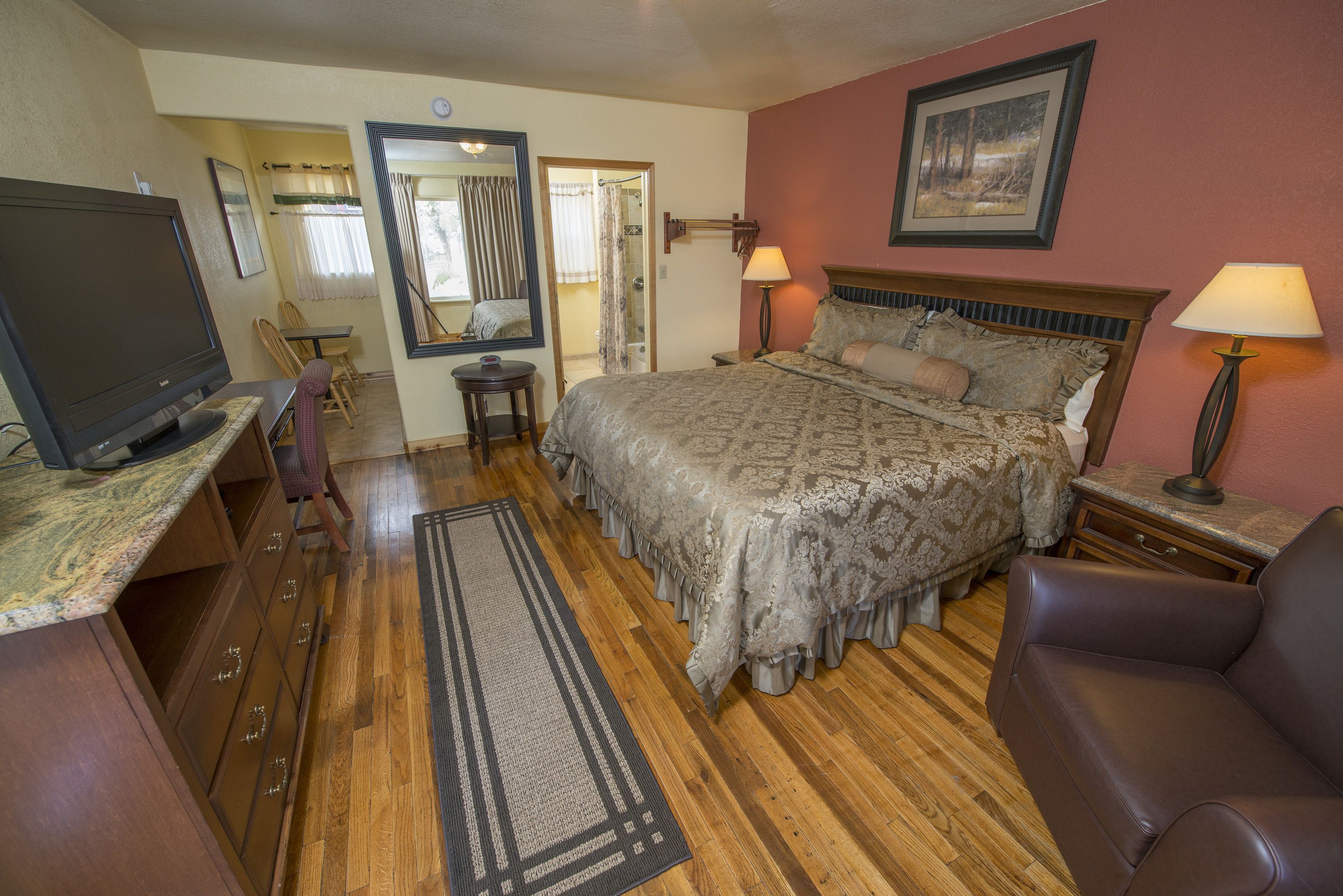 A bedroom with a bed, bedside lamps, a TV, a desk, and a chair.