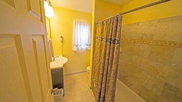 A bathroom with a shower curtain, a toilet, and a sink.