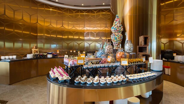 A buffet area with a variety of food items and a decorative Christmas tree. - Novotel Chennai Sipcot (Tirupporur)
