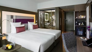A hotel room with a large bed, a desk with a laptop, a glass shower area, and a minibar. - Novotel Chennai Sipcot (Tirupporur)