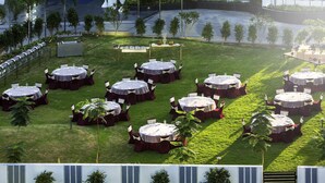 An outdoor event space with round tables, chairs, and flags. - Novotel Chennai Sipcot (Tirupporur)