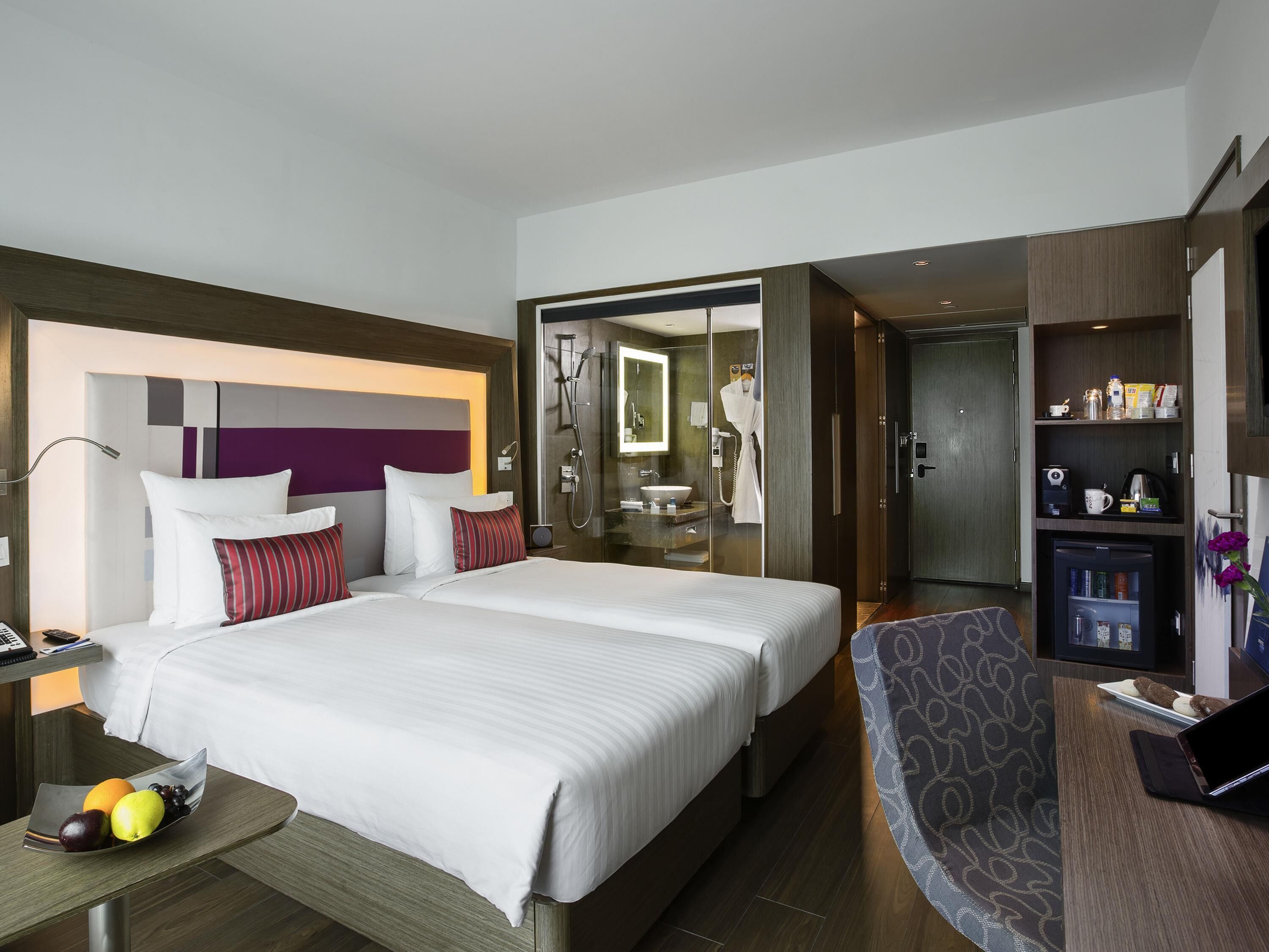 Une chambre d’hôtel avec un grand lit, un bureau avec un ordinateur portable, une salle de bain et un mini-bar.