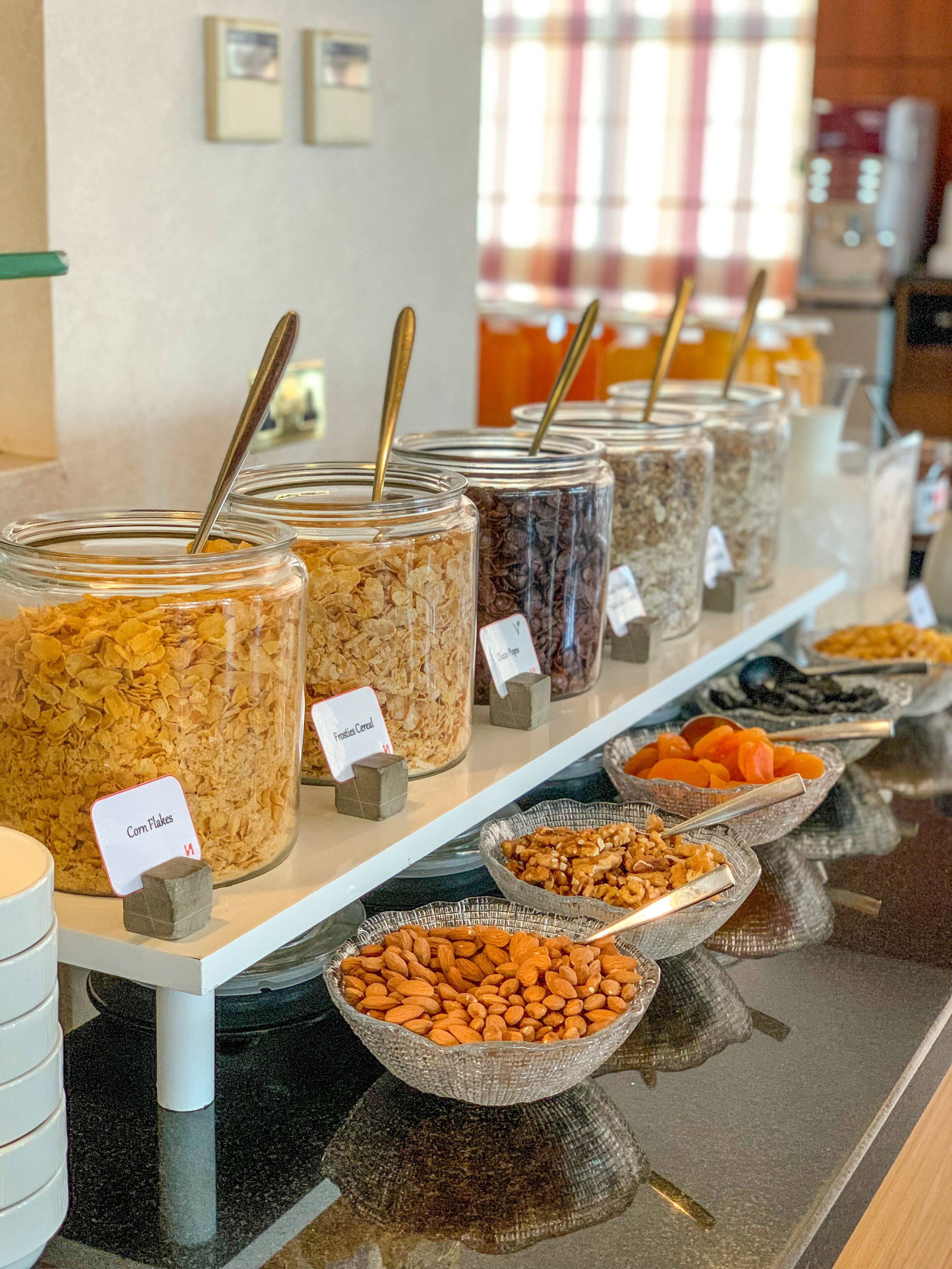 Ein Buffet mit verschiedenen Speisen in Gläsern und Schalen, darunter Müsli, Nüsse und Trockenfrüchte.