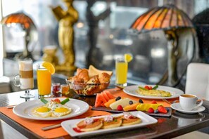 A breakfast setting with plates of eggs, croissants, and fruit, along with coffee and juice. - Swiss-Belhotel Seef Bahrain (Manama)