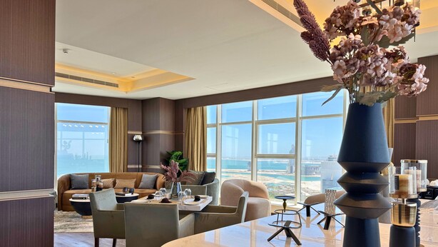 Un moderno vestíbulo de hotel con una zona de estar, un mostrador de recepción y ventanas amplias que ofrecen vistas de la ciudad.